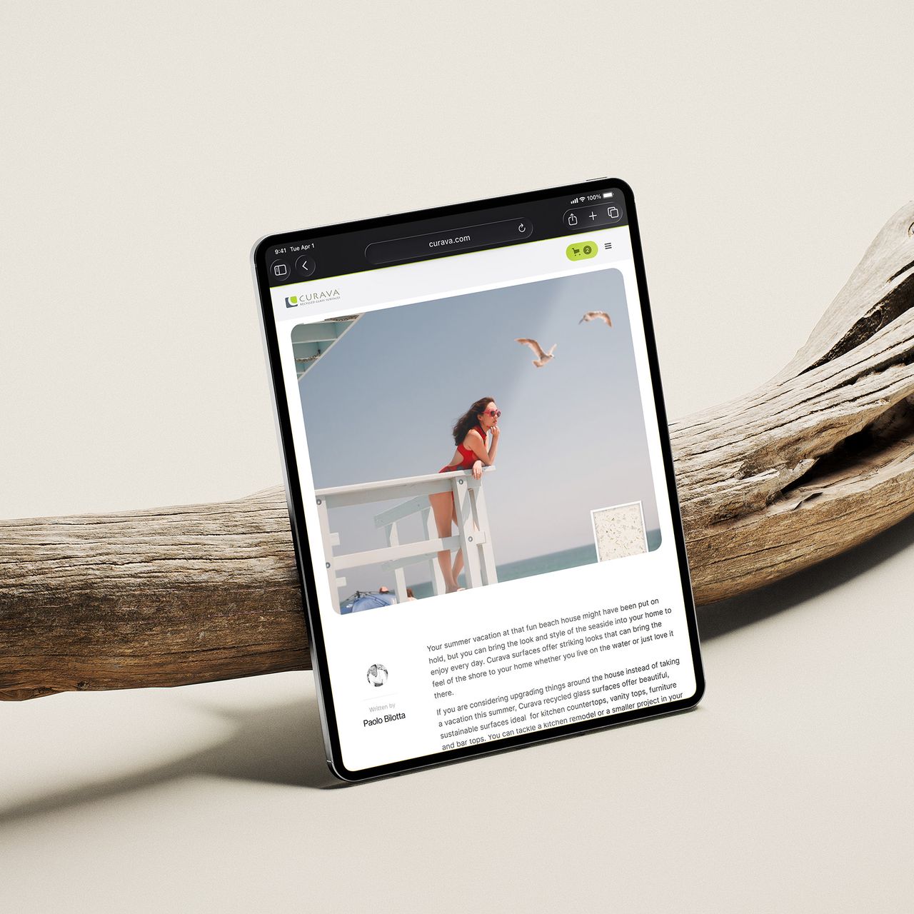 Tablet showing a Curava article, leaning on driftwood
