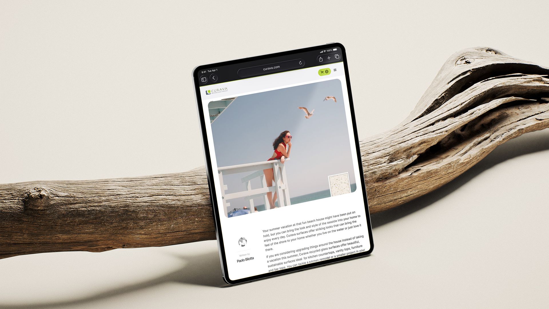 Tablet showing a Curava article, leaning on driftwood