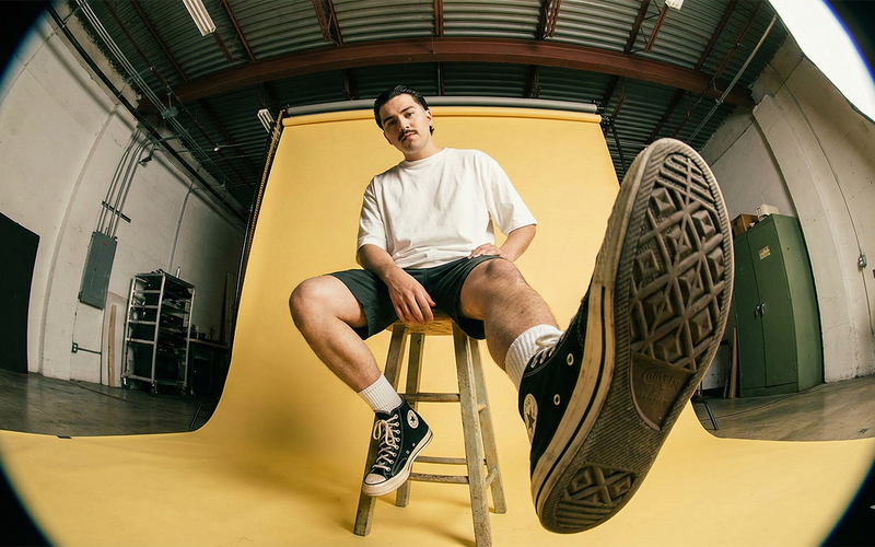 Fisheye photo of a person on a stool with a sneaker sole toward the camera
