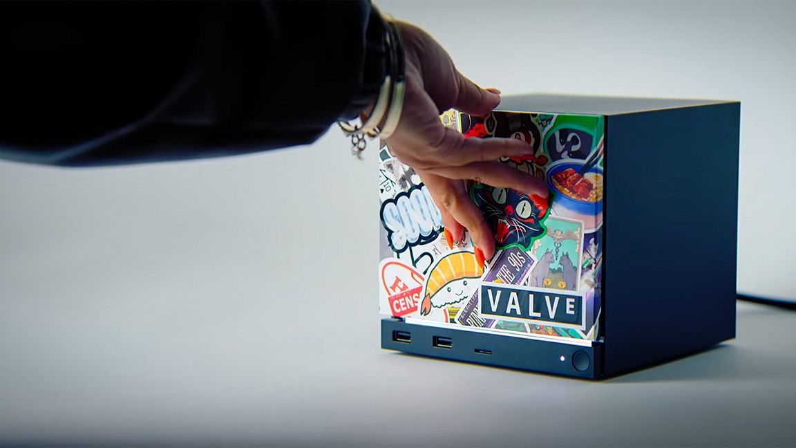 Hand placing stickers on a small black Valve cube