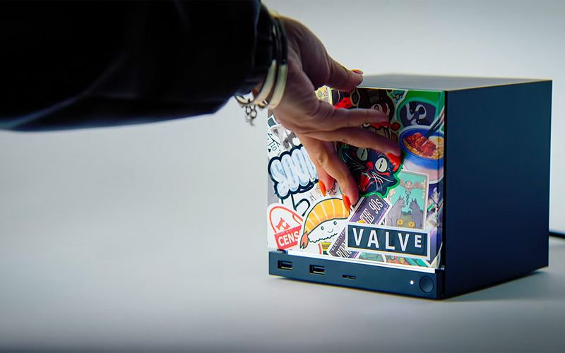 Hand placing stickers on a small black Valve cube